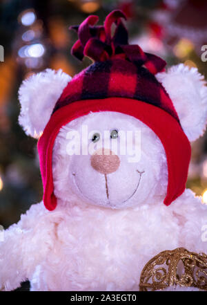 Ein Weißer Teddybär trägt ein rotes plaid Hut und stellt für eine niedliche Winter portrait Stockfoto