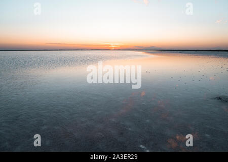 Schönen Sonnenuntergang auf der See. Schönen Sonnenaufgang auf dem See. Die Umwelt zu schützen. Sonne ha Horizont auf Rosa und Violett den Himmel. Stockfoto