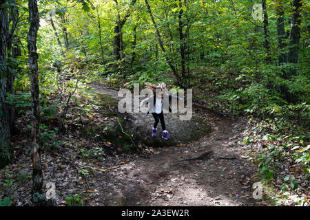 Junge Mädchen Sprung vom Felsen im Wald im Herbst im Park, Slow Shutter, Bewegungsunschärfe. Gatineau Park, Quebec, Ontario. Stockfoto