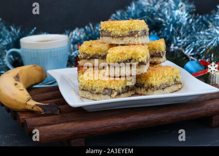 Selbstgemachte Banane Kuchen mit Kokosraspeln - festliches Dessert für Weihnachten, Neujahr, Close-up mit Tasse Kaffee auf den Hintergrund, horizontal Stockfoto