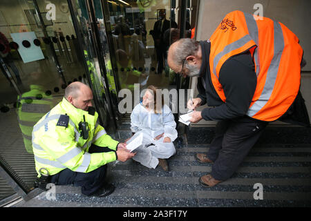 Ein Polizeibeamter liest einem Protestierenden, der sich im Rahmen eines Extinction Rebellion (XR)-Protests vor dem Transportministerium in der Horseferry Road, Westminter, London, am Boden festgeklebt hat, einen Befehl aus Abschnitt 14 vor. Stockfoto