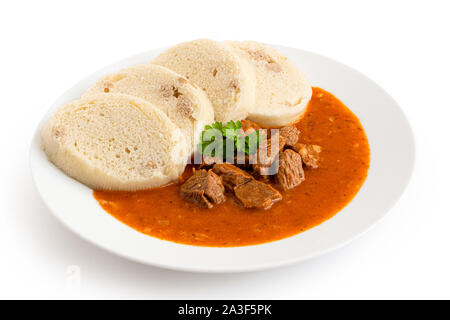 Rindergulasch mit Semmelknödel und Petersilie garnieren auf weißer Keramik Platte isoliert auf Weiss. Stockfoto