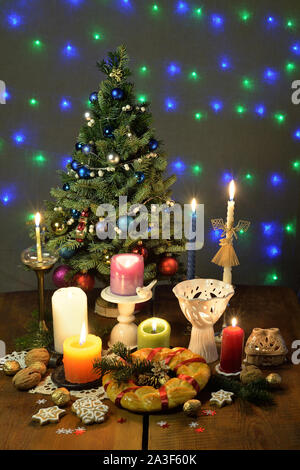 Brennende Kerzen im Kerzenständer, eine Runde rituelle Brot, Lebkuchen Kekse, Walnüsse sind auf dem Holztisch. Stockfoto