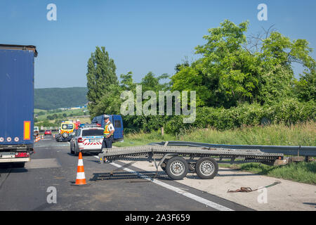 Tatabanya, Ungarn - 25. Juni 2019: Car crash Unfall auf Autobahn. Beschädigte umgeworfen Auto nach Kollision, Krankenwagen, Polizei Auto und bereitgestellte Plattform Stockfoto