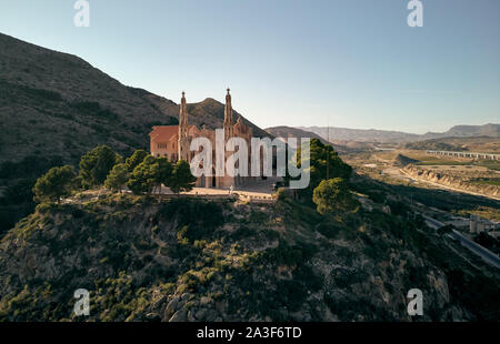 Antenne drone Sicht Heiligtum der Santa Maria Magdalena steigt unter der Oberseite des Rocky Mountain in Novelda Stadt, spanisch Jugendstil Meisterwerk Stockfoto