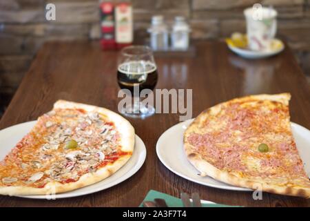 Zwei Scheiben Pizza auf dem hölzernen Tisch serviert. Stockfoto