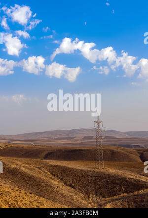 Hochspannung Strommasten in hügeligem Gelände Stockfoto