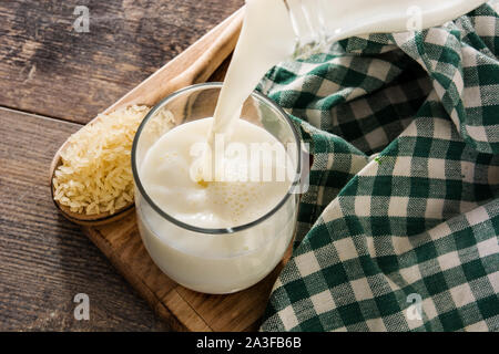 Gießen Reis Milch in Glas auf hölzernen Tisch. Stockfoto