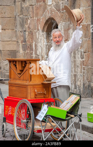 Saint-Malo, Frankreich - 20. Juli 2017: Alter Mann mit langen weißen Brot steht hinter seiner Straße Orgel singen, während sein Musikinstrument für Tipps. Stockfoto