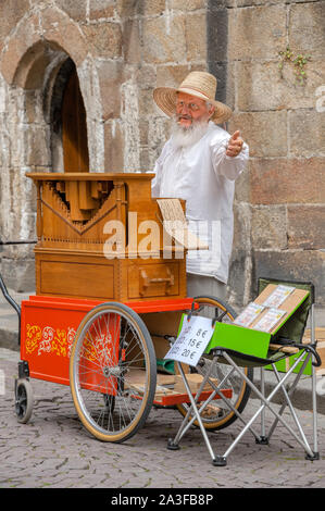 Saint-Malo, Frankreich - 20. Juli 2017: Alter Mann mit langen weißen Brot steht hinter seiner Straße Orgel singen, während sein Musikinstrument für Tipps. Stockfoto