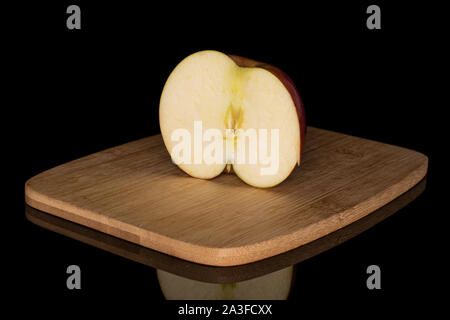 Die Hälfte der rote Apfel jonagold auf Bambus Schneidbrett auf schwarzem Glas isoliert Stockfoto