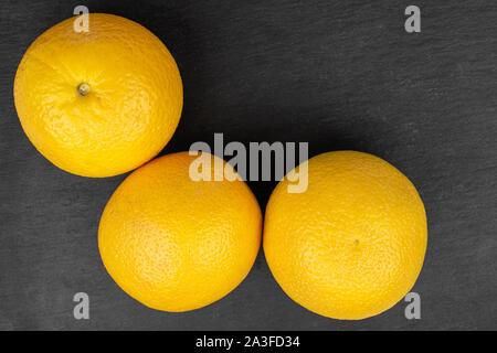 Gruppe von drei ganzen frischen hellen orange flatlay am grauen Stein Stockfoto