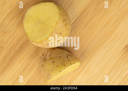 Gruppe von zwei Hälften von Roh braun Kartoffel flatlay auf hellem Holz. Stockfoto