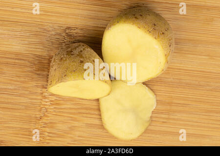 Gruppe von zwei Hälften einer Scheibe rohen braun Kartoffel flatlay auf hellem Holz. Stockfoto