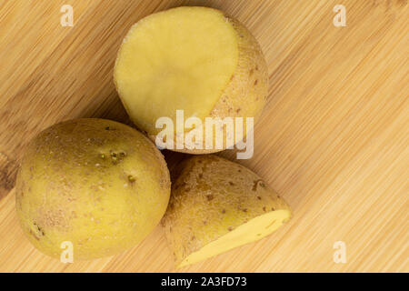 Gruppe von einer ganzen zwei Hälften von Roh braun Kartoffel flatlay auf hellem Holz. Stockfoto