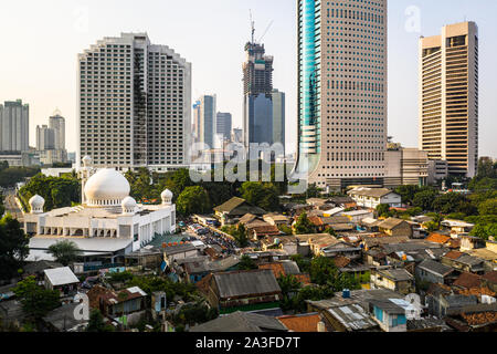 Kontrast in Jakarta Stadtzentrum mit modernen Wolkenkratzern, eine große Moschee und einem sehr gedrängten niedrigen Einkommen Wohnviertel in Indonesien Hauptstadt Stockfoto