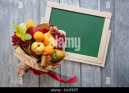 Ungewöhnliche leckeres Obst Bouquet. Teacher's Tag. Kopieren Sie Platz. Green School Board auf einer hölzernen vintage Hintergrund. Stockfoto