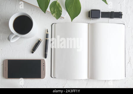 Einen Stift auf einem Notizbuch aus Papier neben einem Buch und einer Tasse mit Kaffee. Inspiration am Arbeitsplatz mit der leere Raum für Editor's Text. Stockfoto
