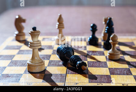 Schwarzer König liegt am Fuß der Weißen Königin auf dem Schachbrett closeup besiegt Stockfoto