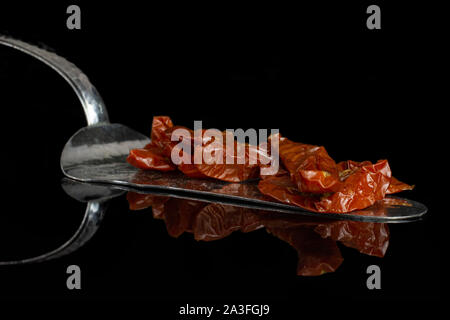 Viele Scheiben trockene rote Kirsche Tomate mit Kuchen Spachtel auf schwarzem Glas isoliert Stockfoto