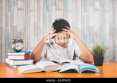 Betonte Student Learning hart mit Büchern in Prüfungen Vorbereitung überwältigt fühlen, während sein Kopf wegen der niedrigen und erschöpft Stockfoto