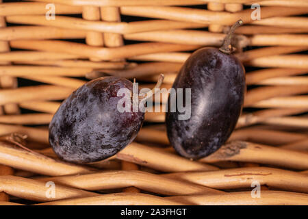 Hinter der Gruppe aus einer ganzen Hälfte frische schwarze Traube mit geflochtenen Rattan Stockfoto