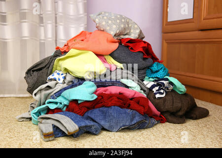 Stapel von achtlos verstreut Kleidung auf dem Boden. Stockfoto