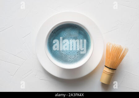 Preisverleihung traditionell blau Matcha Tee in der Schüssel und Bambus chasen auf weißem Beton. Ansicht von oben. Stockfoto