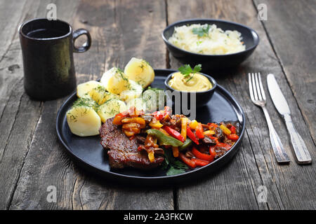 Gegrilltes Schweinefleisch Hals mit Gedünstetem bunter Pfeffer serviert mit Kartoffeln, Senfsauce und Speck-Krautsalat Stockfoto