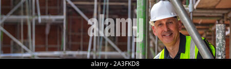 Panoramablick Web Banner lächelnd männlichen builder Foreman, Bauarbeiter, Ingenieur, Gutachter, Bauleiter oder Architekten, trägt einen weißen harten Hut und Hi Stockfoto