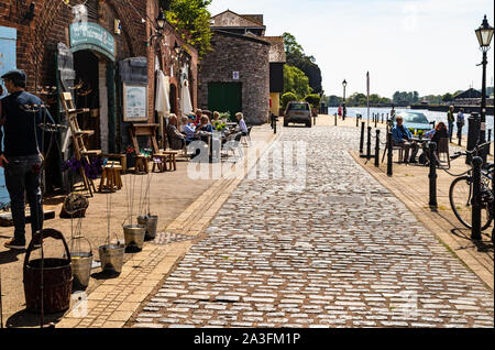 Historische Kai Gebäude und gepflasterte Straße Ansicht: Keller Café und Shop im Alten Keller durch den Fluss Exe an einem sonnigen Herbstnachmittag, Exeter Quay Stockfoto