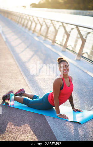 Strahlend schöne Frau Yoga auf der Brücke Stockfoto