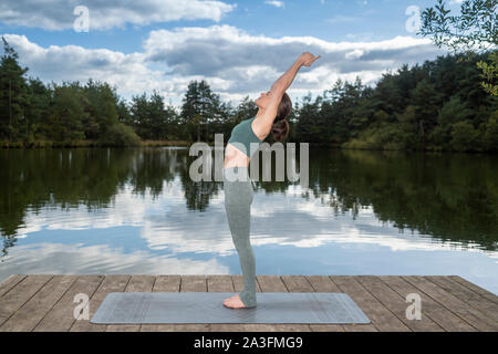 Frau Yoga üben auf einem Steg an einem See, Berg darstellen, Stockfoto