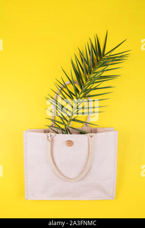 Umweltfreundliche Baumwolle Tasche mit palm leaf auf gelbem Hintergrund, Kopieren, minimalistisch Natur Stil. Umweltschutz Recycling Konzept Stockfoto