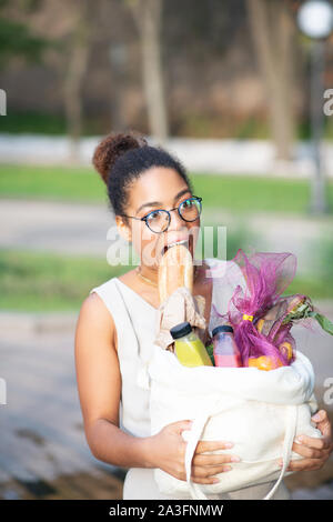 Lustige Frau beißen Baguette beim Gehen nach Hause nach Supermarkt Stockfoto