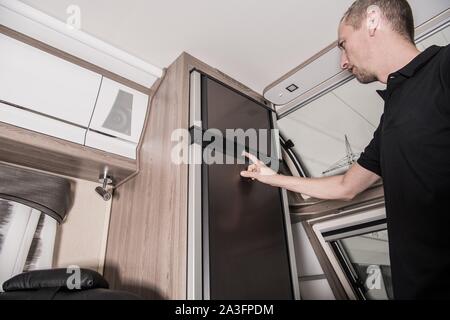 RV Camping Kühlschrank Prüfen durch den Eigentümer. Vorbereitung Recreational Vehicle für die Saison. Travel Trailer Interieur. Stockfoto