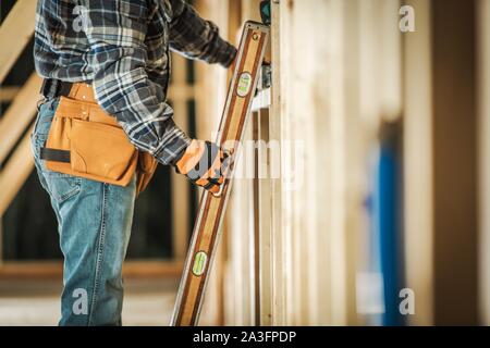 Auftragnehmer Arbeiter die Wasserwaage Werkzeug, um sicherzustellen, dass der Holzrahmen Ausrichtung korrekt ist. Bau Werkzeuge und Technologien. Stockfoto