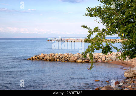 Seitenansicht eines Pier am Issyk-Kul See mit einer Bergkette mit schneebedeckten Gipfel am Horizont gegen einen bewölkten Himmel Stockfoto