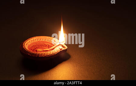 Happy Diwali. Ton diya Kerze beleuchtet in Dipavali, Hindu Festival der Lichter. Traditionelle Öllampe auf dunklem Hintergrund, kopieren. Stockfoto