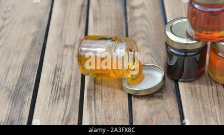 Öffnen Sie umgeworfen, Honey Pot mit Honig tropft in die Deckel auf einem Holztisch Stockfoto