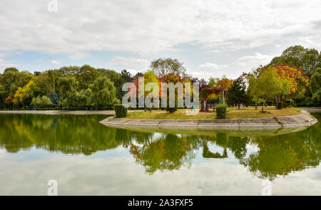 Outdoorsfall Landschaft, Bäume auf einer kleinen Insel an einem See ein Freizeitpark in Ploiesti, Rumänien Stockfoto