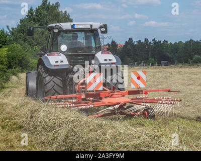 Traktor drehen Heu in einem Feld Stockfoto