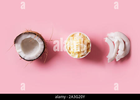 Dehydriert, frische und getrocknete coconut Chips in weißen Schüsseln auf rosa Hintergrund. Blick von oben. Stockfoto