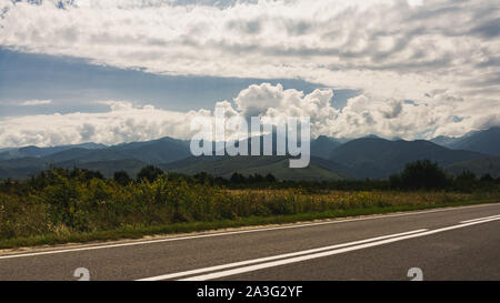 Malerischer Blick auf Wolken, Berge und Straße im Sommer, am Fuße der Karpaten, Rumänien Stockfoto