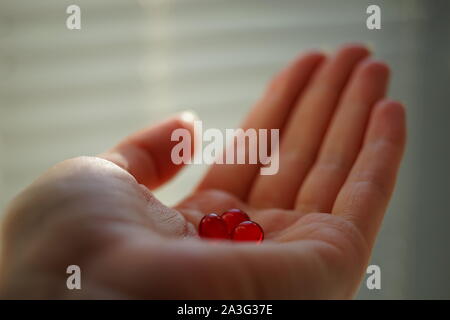 Rote runde Vitamine im menschlichen Palm. Behandlung oder Drogen nehmen. Stockfoto