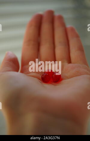 Rote runde Vitamine in der weiblichen Palm. Behandlung oder Drogen nehmen. Stockfoto