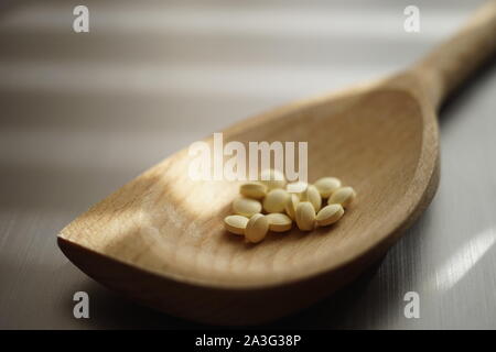 Medizinische Pillen in einem hölzernen Löffel auf dem Tisch, natürlichen Hintergrund, Seitenansicht. Stockfoto