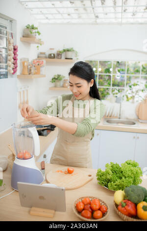 Hübsche junge Frau Smoothie mit Rezept auf der Tablette Stockfoto