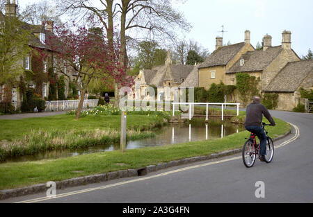 Ein Radfahrer, reitet neben das kleine Auge stream im hübschen Dorf Cotswold Lower Slaughter, England, UK, 23/4/02. Stockfoto