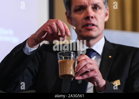 Stockholm, Schweden. 8. Oktober, 2019. Ulf Danielsson, Mitglied des Nobelkomitees für Physik, fügt Zucker in eine Tasse Kaffee, da macht er eine Erklärung bei der Bekanntgabe der 2019 Nobelpreis für Physik in Stockholm, Schweden, 8. Oktober, 2019. Der Nobelpreis für Physik 2019 von drei Wissenschaftlern geteilt werden, der Königlichen Akademie der Wissenschaften in Stockholm bekannt gegeben am Dienstag. Credit: Zheng Huansong/Xinhua/Alamy leben Nachrichten Stockfoto